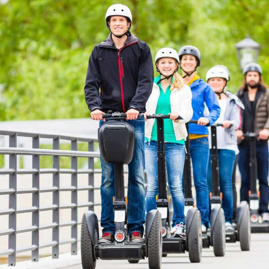 group of people smiling and wearing helmets riding segways in a guided segway tour of madrid