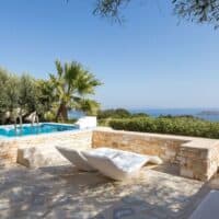 2 sun lounges by a pool with sea view at Calme Boutique Hotel in Paros, Luxury Accommodation In Paros