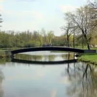 a bridge over a lake with its reflection on the lake inside a park