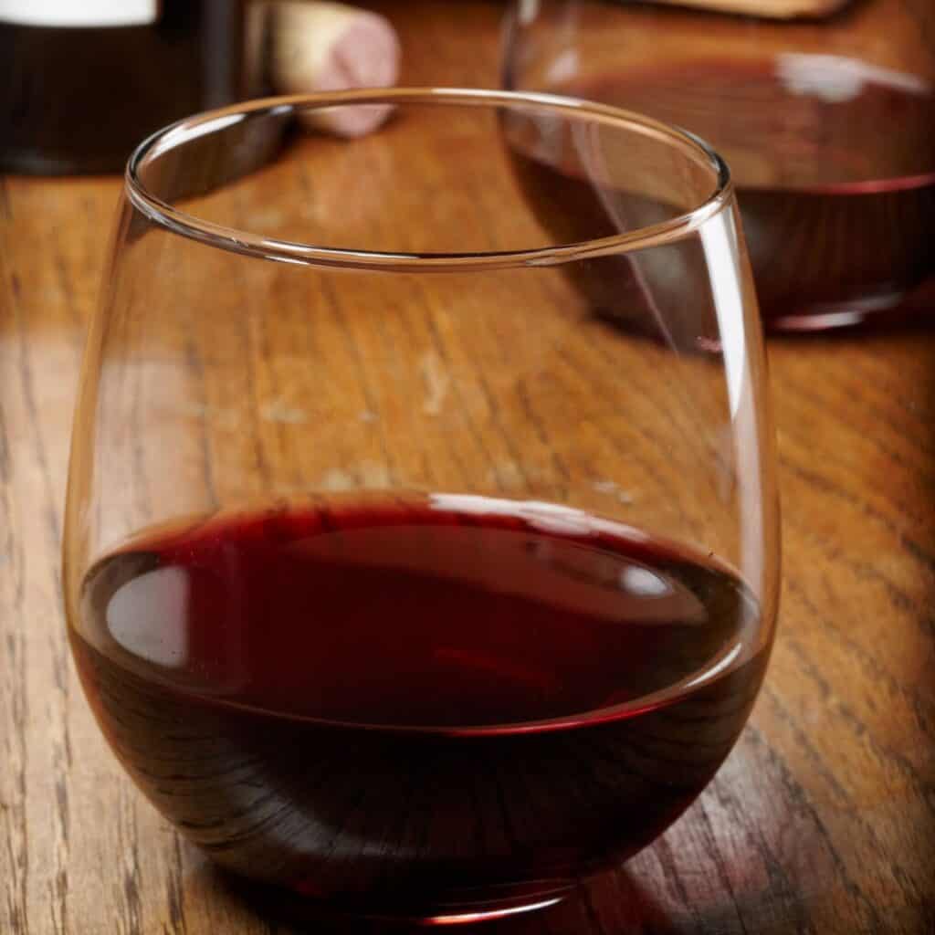 two stemless glasses of red wine on a wooden table