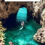 Pinterest pin about Algarve in August showing a photo of a scenic coastline featuring towering cliffs, rocky caves, and a small beach with turquoise water.