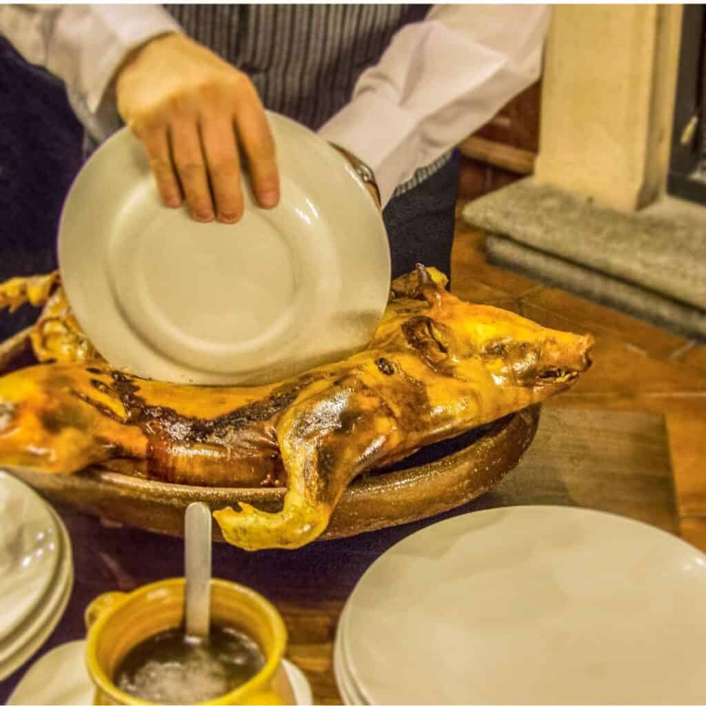 A plate of roasted suckling pig (cochinillo asado) being served and cut in a high-end restaurant in Madrid, Spain