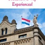 A Pinterest pin about Luxembourg Bucketlist showing an old building with a statue of a woman holding a bouquet of flowers and a Luxembourgish flag waving in the wind.