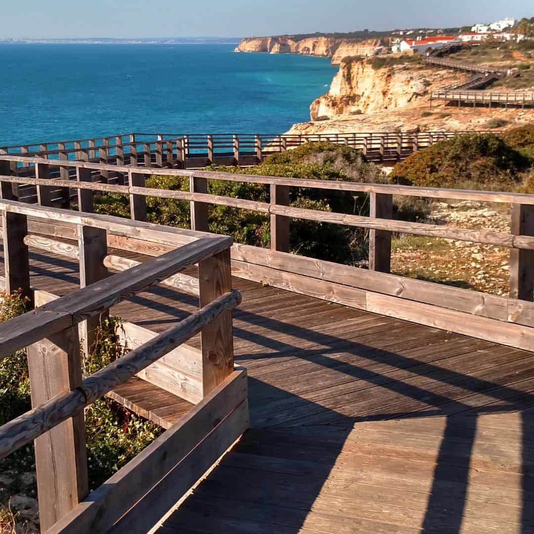 Wooden boardwalk overlooking a scenic coastal cliff with a clear blue ocean in Carvoeiro, Portugal. This is one of the best things to do in Albufeira in September.