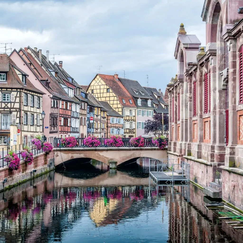 : A picturesque canal lined with colorful half-timbered houses and a bridge adorned with flowers in Strasbourg, one of the best weekend trips from Luxembourg.