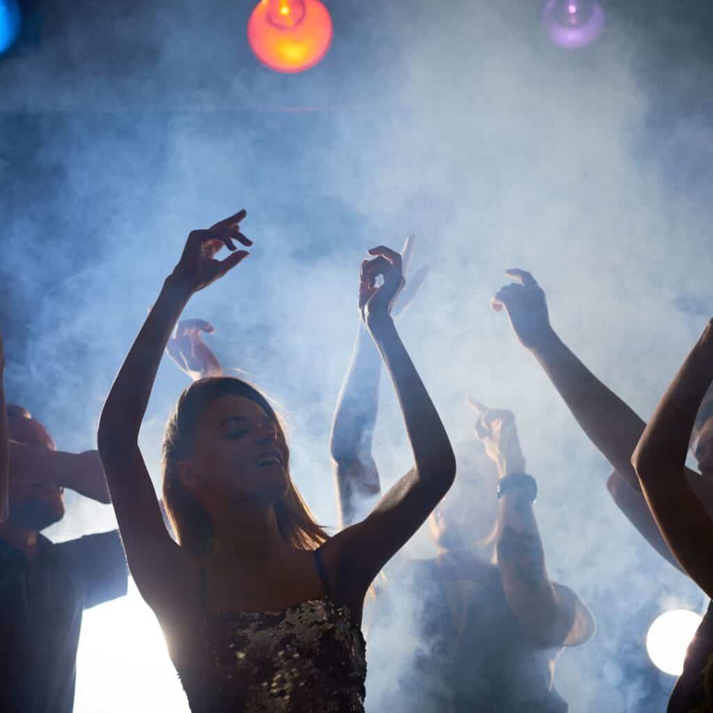 People dancing with their arms raised at a nightclub in Paros, Greece