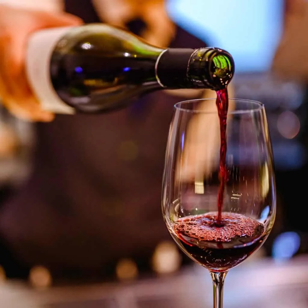 a person pours red wine into a glass