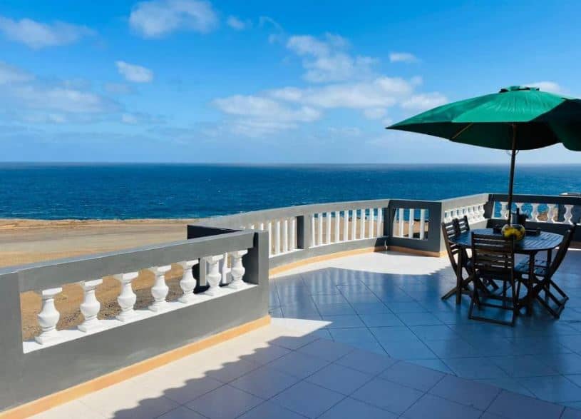 large balcony with a table located bright on the beach at Residencial Sol Point Art in Ponta do Sol, cape Verde