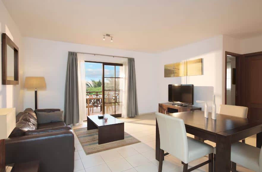 living room with sofa, TV, dining table and balcony at Meliá Tortuga Beach in Cape Verde