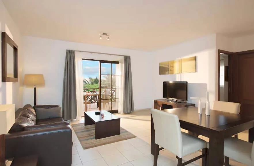 living room with sofa, TV, dining table and balcony at Meliá Tortuga Beach in Cape Verde