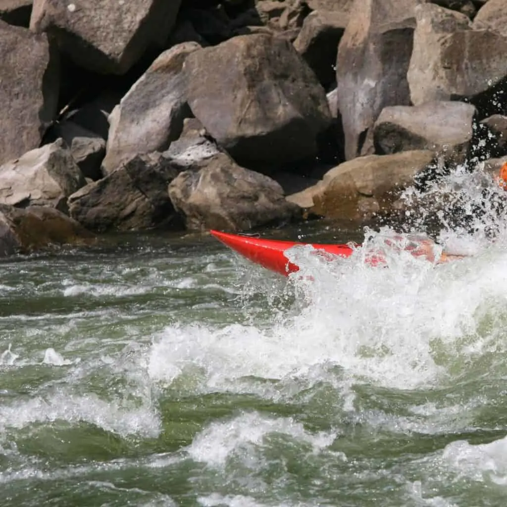 a person in a red kayak paddling through rapids