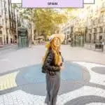 a person in a hat walking on a cobblestone street in barcelona, spain