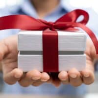 a person holding a gift box with a red ribbon