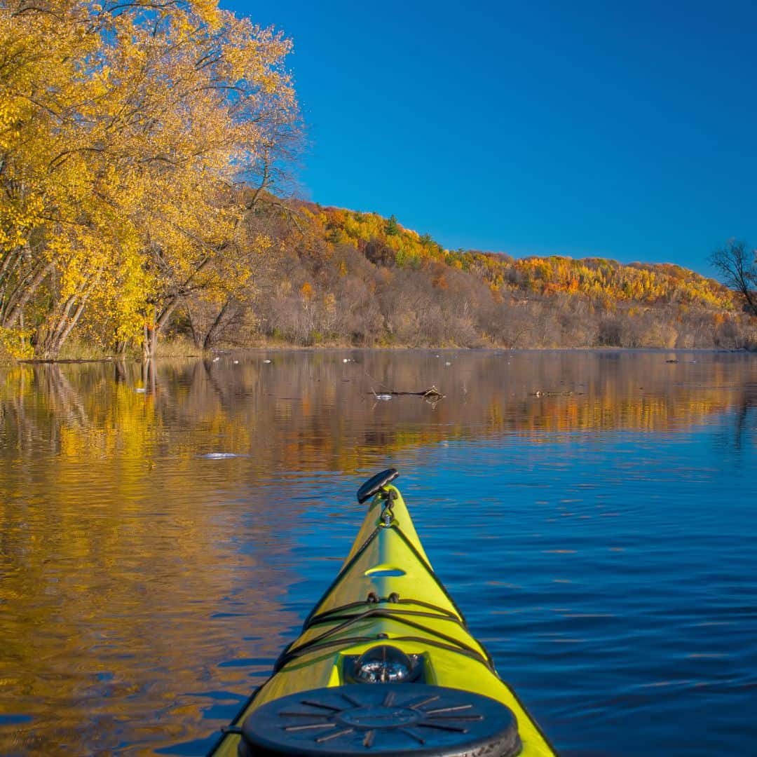 a kayak on the river with autumn trees in the background