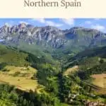 A scenic landscape in Northern Spain featuring a valley with rolling green hills, mountains in the distance, and a small village nestled among the trees. The text 