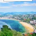 A panoramic view of San Sebastian, Spain, showcasing a crescent-shaped beach, a bay, and the city skyline in the distance. The text 