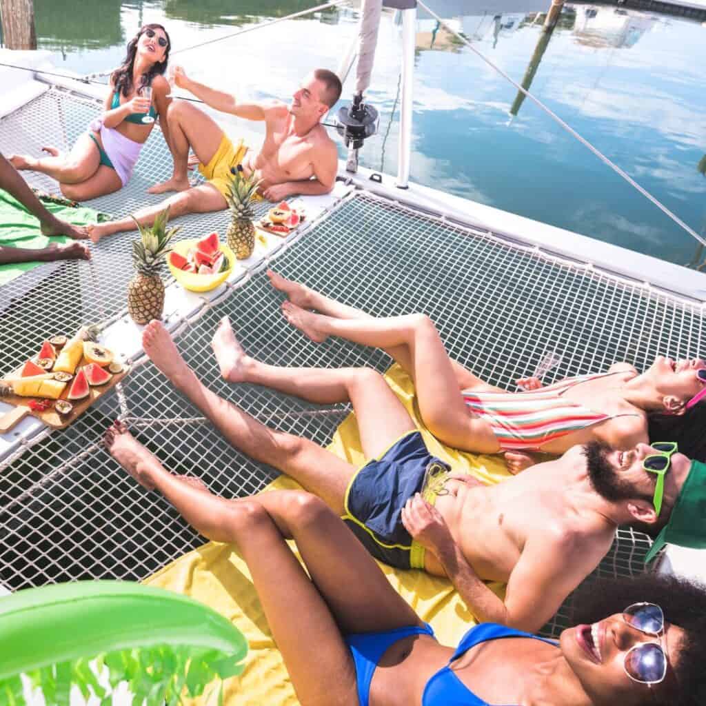 a group of people relaxing on the deck on a catamaran with fruits and drinks