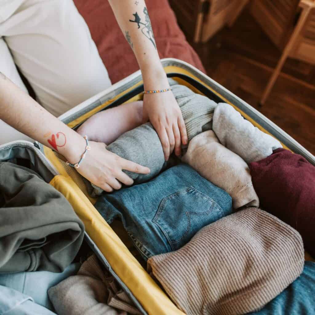 a person is packing clothes in an open suitcase