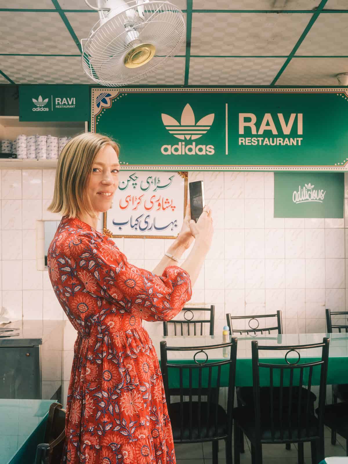 a woman in a red dress in a restaurant with a phone taking a picture