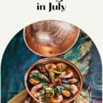 seafood stew in a copper pan on a wooden cutting board