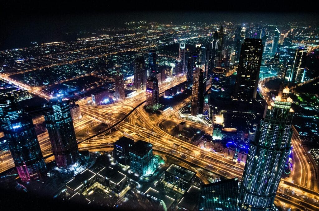 A stunning aerial view of Dubai's illuminated skyline at night, showcasing its modern architecture and busy roads.