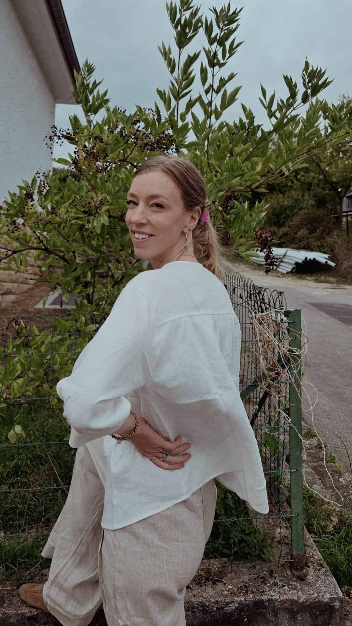 Linen for Travel Why I Switched to Linen for Travel Lintico Discovery | Paulina | Woman wearing a white top, and linen pants with a garden at the background