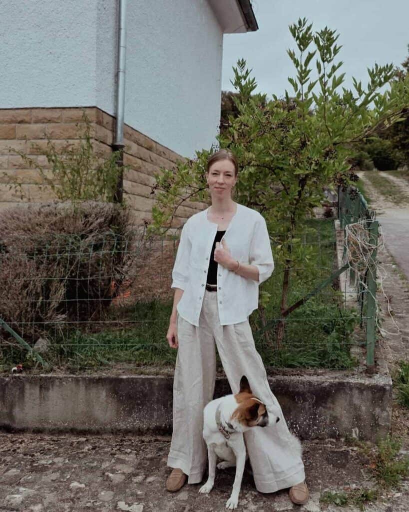 Why I Switched to Linen for Travel Lintico Discovery | Paulina | Woman wearing a black shirt, white top, and linen pants with a dog near a garden at the background